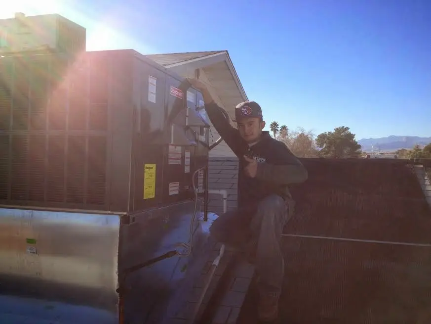 HVAC technician performing Air Duct Repair on a rooftop unit in Foxborough